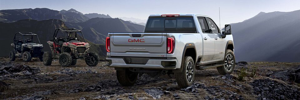 Le GMC Sierra AT4 2023 stationné sur une colline rocheuse à côté de deux véhicules.