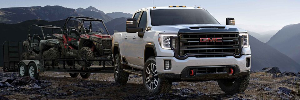 Le GMC Sierra AT4 2023 remorque deux véhicules sur un terrain rocailleux.