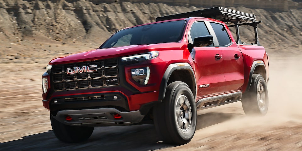 2024 GMC Canyon AT4 driving on dusty terrain.