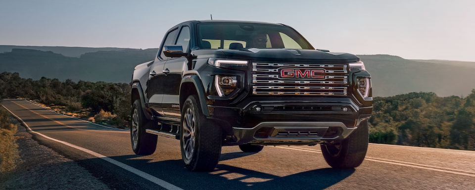 Front view of the 2024 GMC Canyon Denali driving on the road.