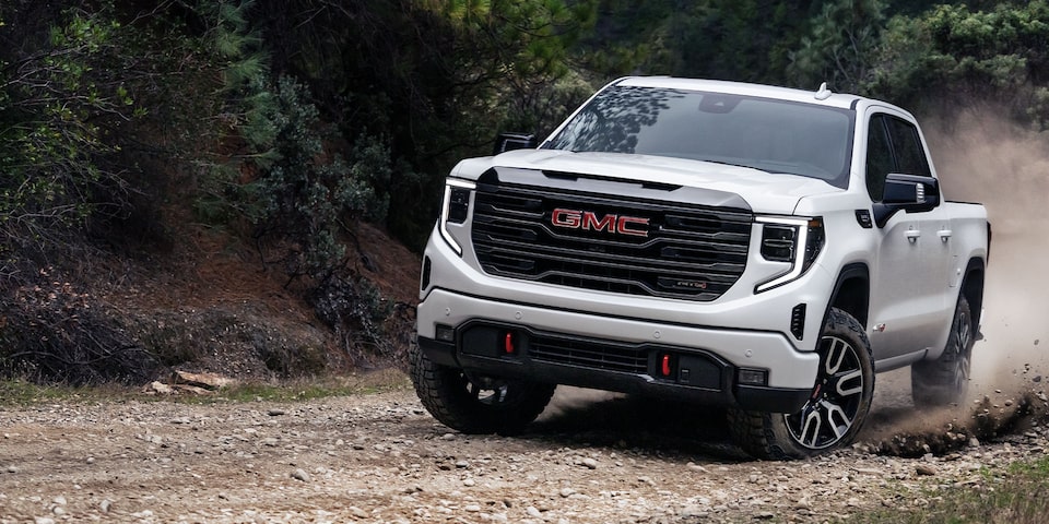 The 2024 GMC Sierra 1500 AT4 driving on the road by the seaside.