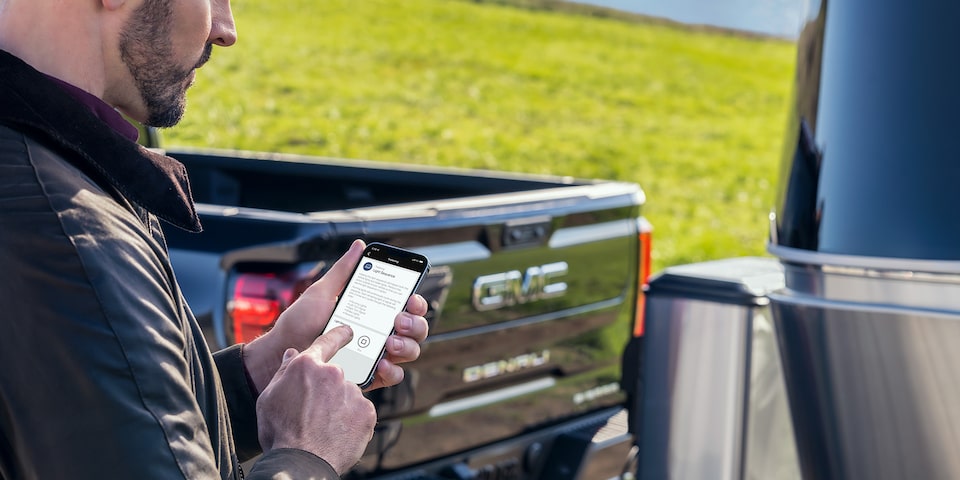 A person using the myGMC Mobile App outside the 2024 GMC Sierra 1500 AT4.