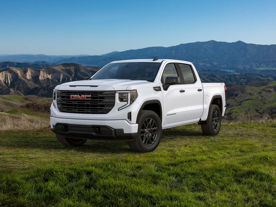 The 2024 Sierra 1500 parked on a grassy terrain by the hillside.