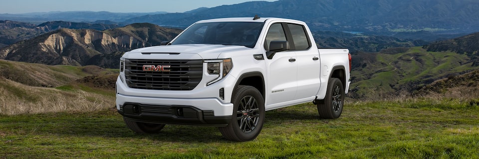 Le GMC Sierra 1500 2024 stationné dans un champ à côté d’une colline.