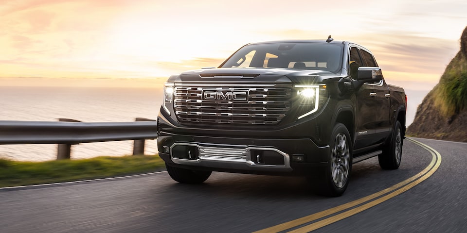 The 2024 GMC Sierra 1500 Denali drving on a road by the seaside.