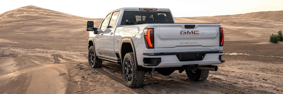 Le GMC Sierra AT4 2023 stationné sur une colline rocheuse à côté de deux véhicules.