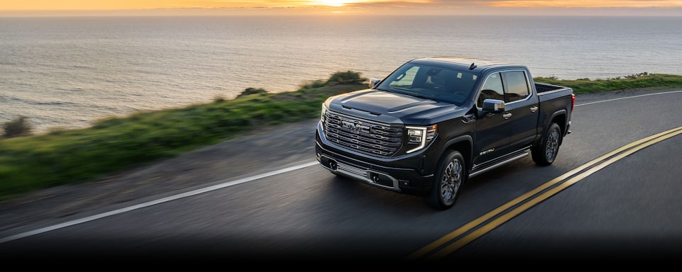 The 2024 GMC Sierra 1500 driving on a road by the seaside.