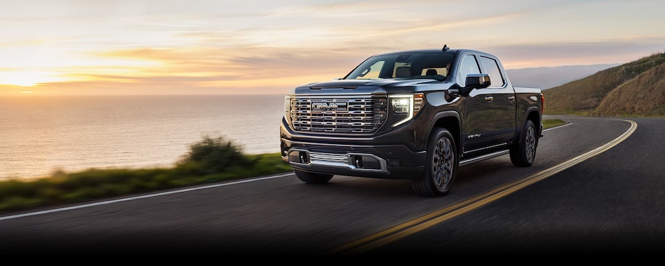 Driving the 2024 GMC Sierra 1500 on a road by the seaside.