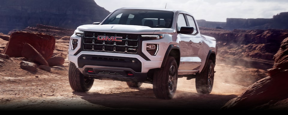 2024 GMC Canyon driving on a dusty dune.