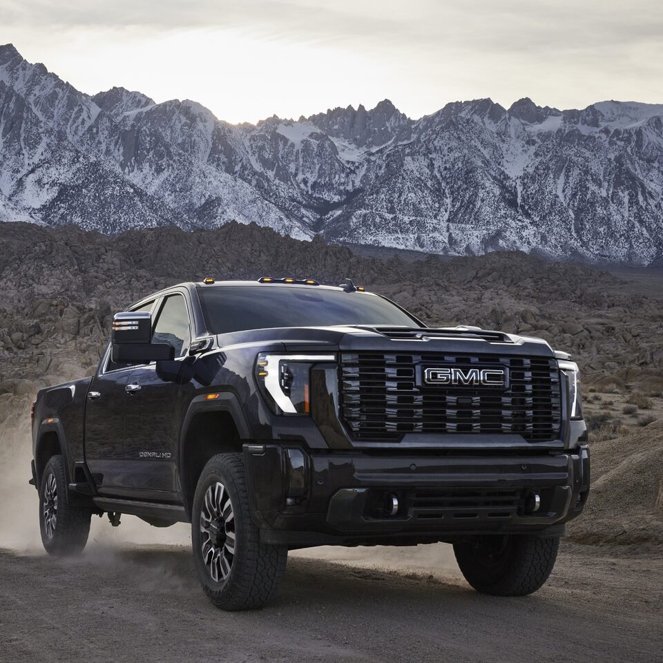 The 2024 GMC Sierra HD driving by the mountains.