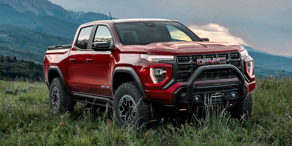 Front-side view of a 2025 GMC Canyon AT4 parked alone in a grassy field.