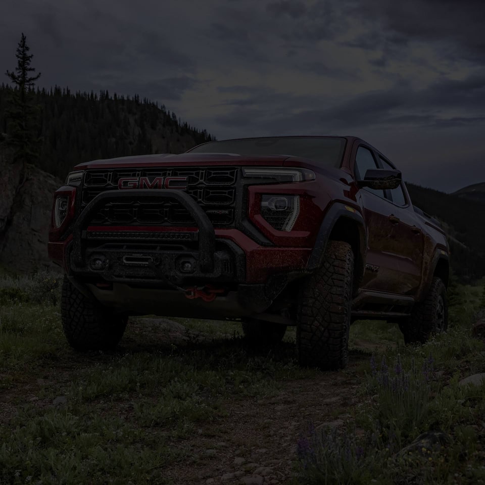 Three-quarters view of a Red 2025 GMC Canyon parked alone in the mountains.