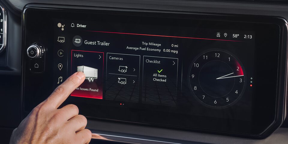 Vue rapprochée d’une personne qui appuie sur le bouton d’une fonction du système d’infodivertissement.