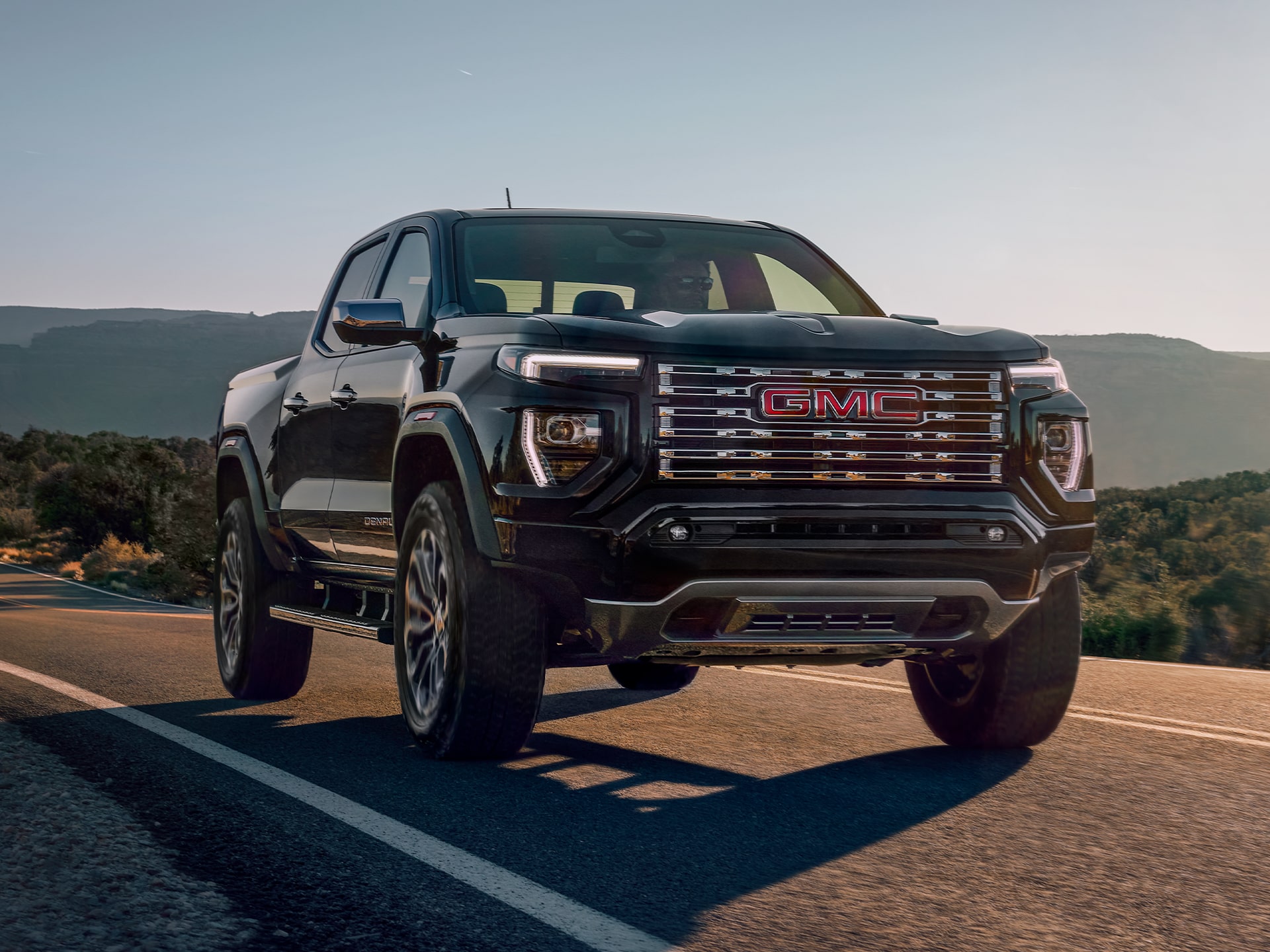 Vue latérale avant du GMC Canyon Denali 2026 en mouvement seul sur la route.