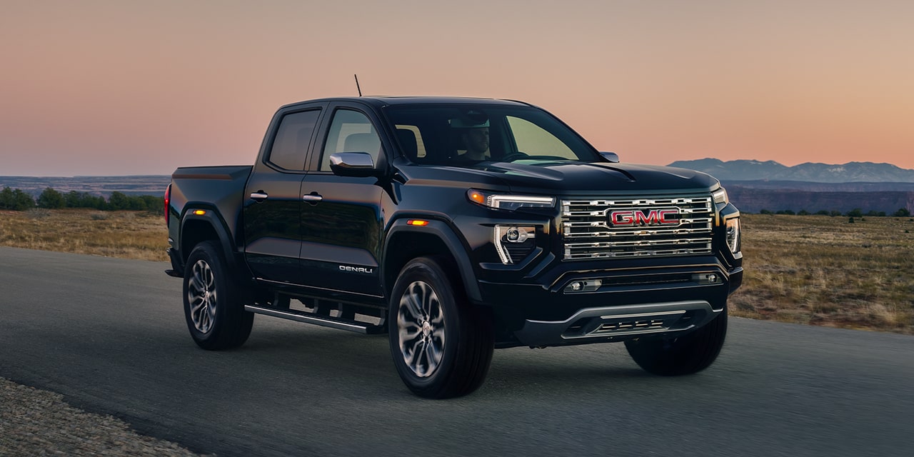 Le GMC Canyon Denali 2026 en mouvement seul sur la route au coucher du soleil.