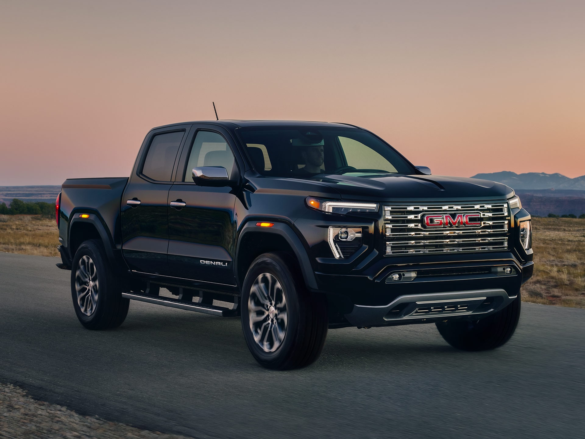 Front-side view of the 2026 GMC Canyon driving alone on a countryside road.