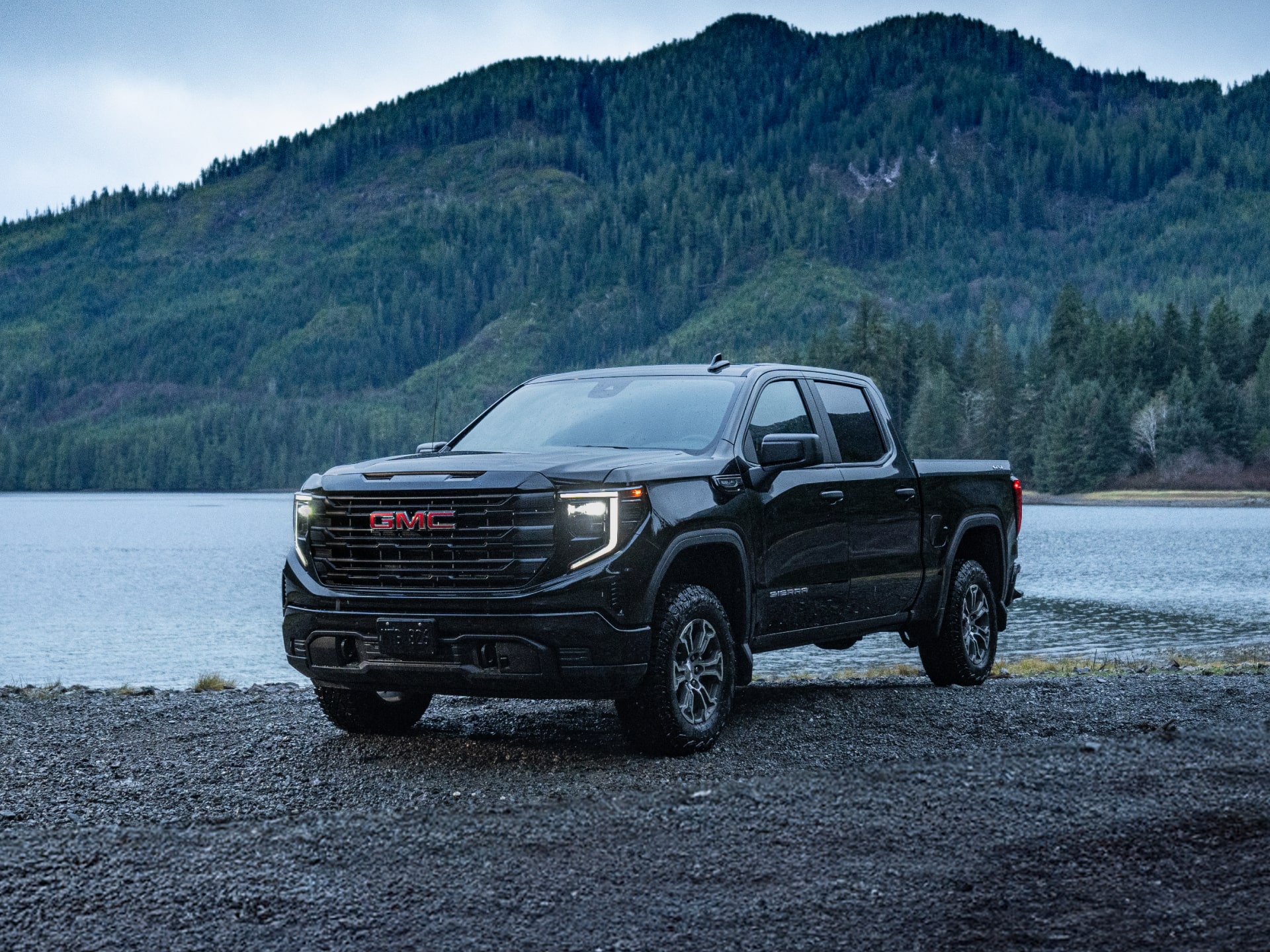 Front Three-Quarters View of a Red 2026 GMC Sierra 1500 Parked in a Forest.