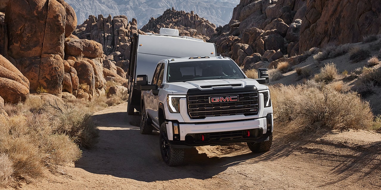 The 2026 GMC Sierra HD Heavy Duty AT4 Truck Hauling a RV Through a Dirt Road.
