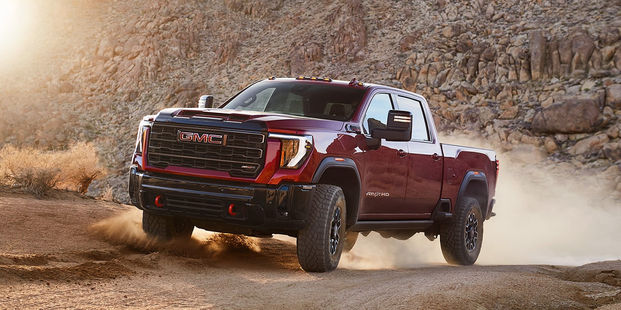 Wide Front Three-Quarters View of a 2026 GMC Sierra HD AT4 Truck Driving Through the Mountains.