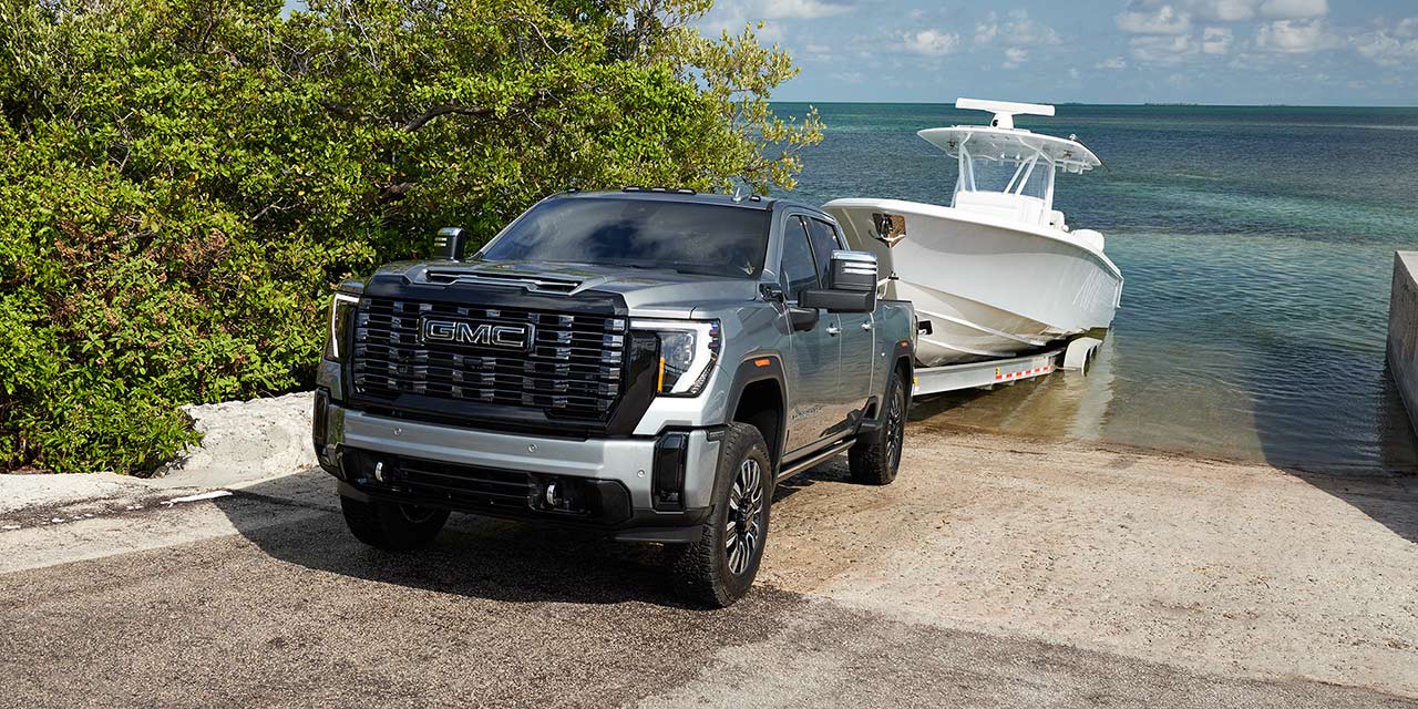 Three-Quarter View of a 2026 GMC Sierra HD Denali on the Boat Ramp Hauling a Boat Out of the Lake.