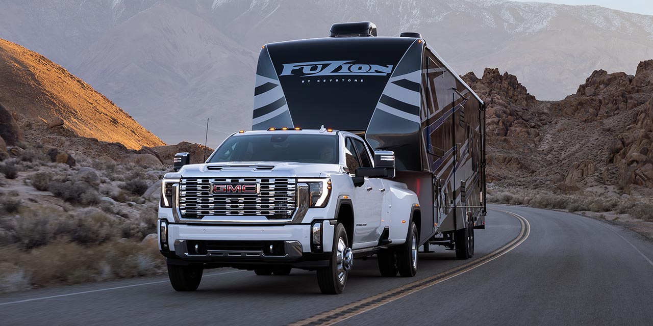 A 2026 GMC Sierra HD Denali Truck Hauling a RV Through the Mountains at Dusk.