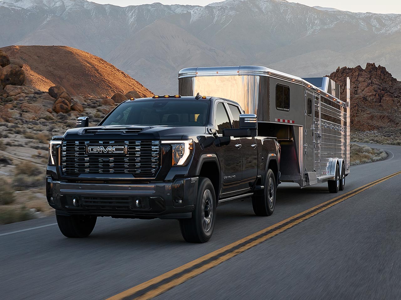 A 2026 GMC Sierra HD Denali Luxury Truck Hauling a Trailer Through the Mountains at Dusk.