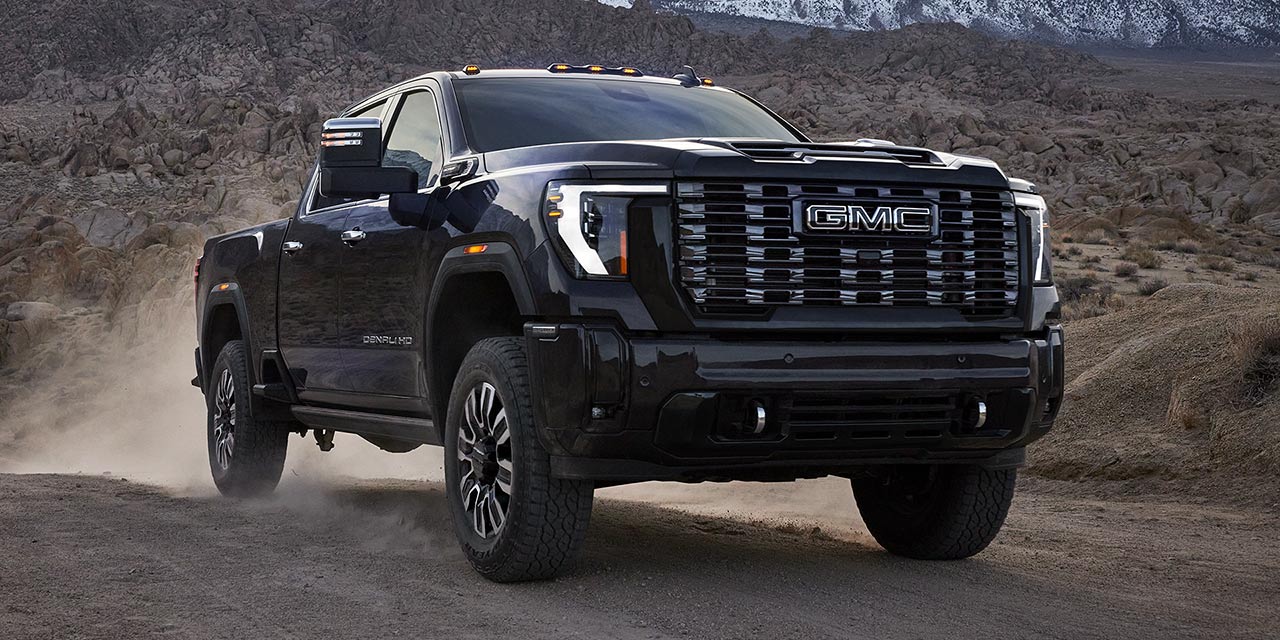 The 2026 GMC Sierra HD Denali Truck Driving Through a Mountain Road and Kicking up Dust.