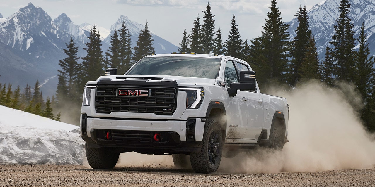 Front-side view of the 2026 GMC Sierra HD Truck Driving Out from a Forest.