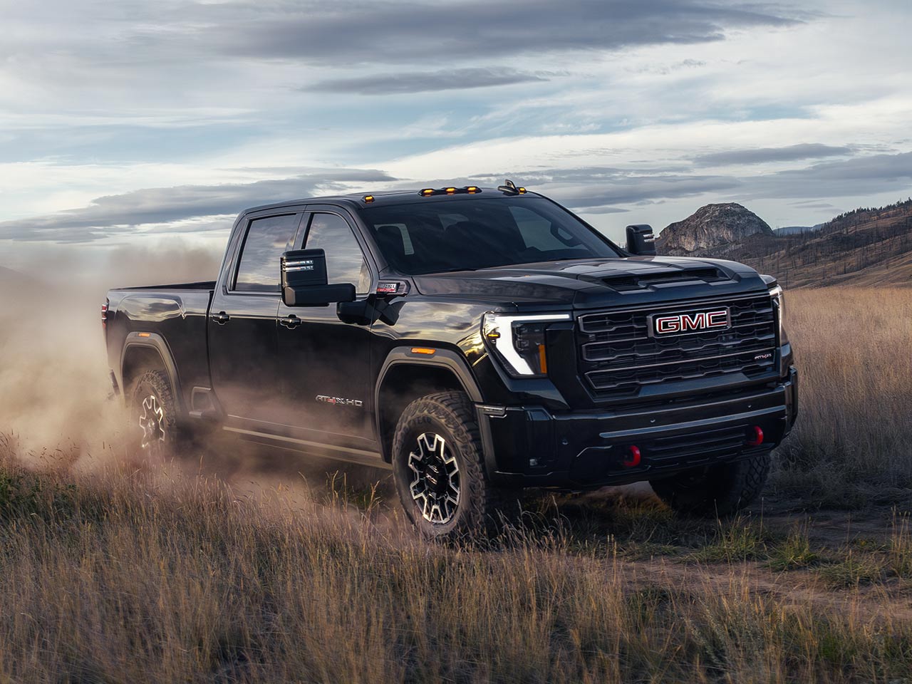 Front-side view of the 2026 GMC Sierra HD Truck Driving Down a Dirt Road.