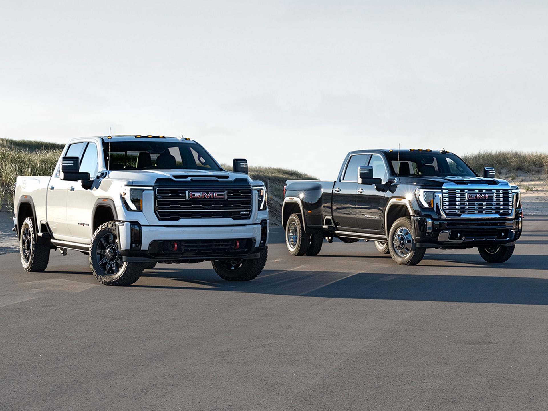 Three 2026 GMC Sierra HD Pickup Trucks Parked Near Each Other Outdoors.
