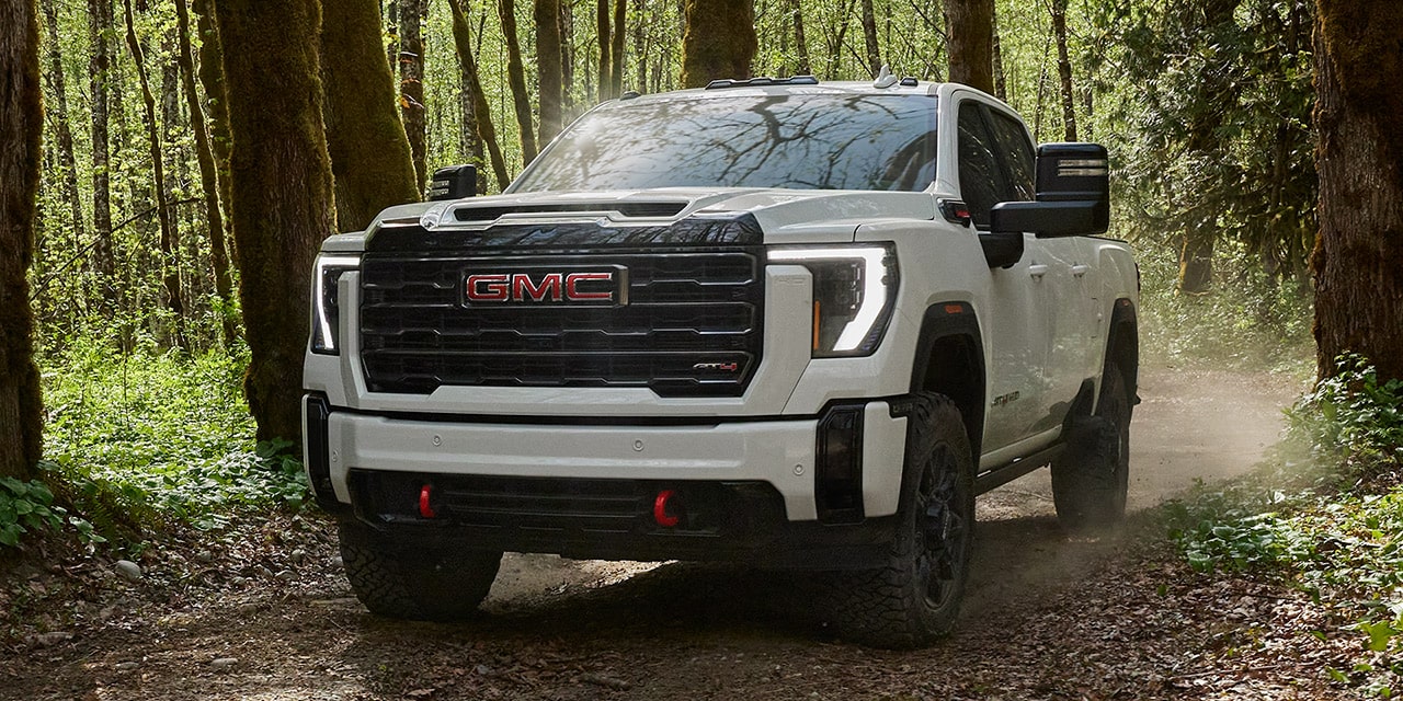 Front View of the 2026 GMC Sierra HD Pro Truck Driving Through a Green Forest.