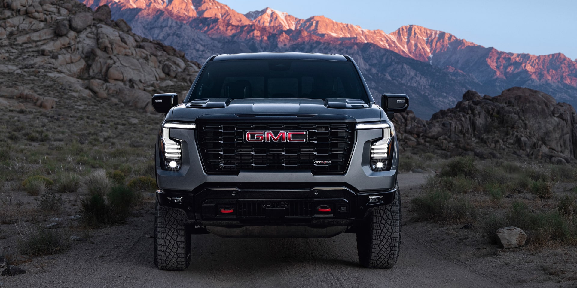 Vue de face d’un GMC Sierra 1500 2027 gris devant un paysage montagneux accidenté