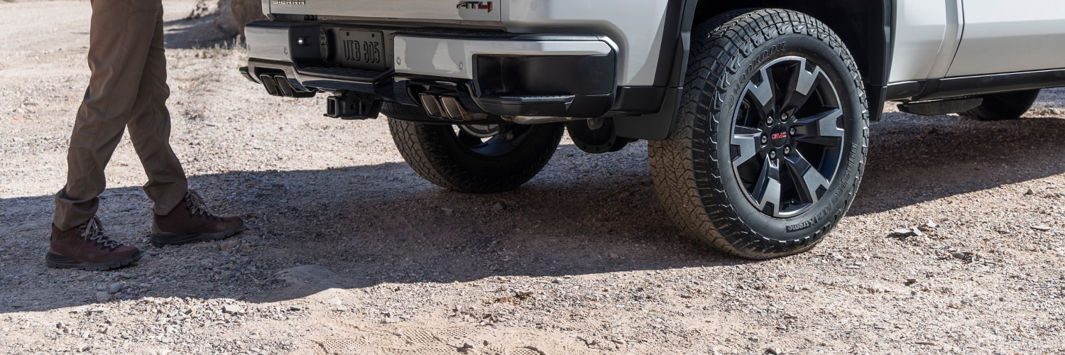 GMC Sierra 1500 2027 gris foncé remorquant un bateau blanc sur une remorque au bord de l’eau