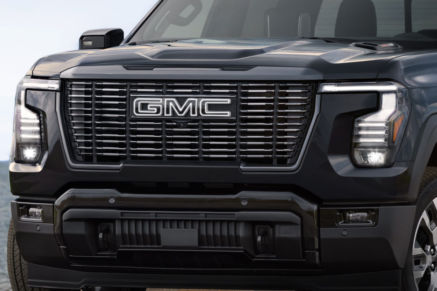 Vue de face d’un GMC Sierra 1500 Denali foncé avec calandre imposante et phares DEL distinctifs