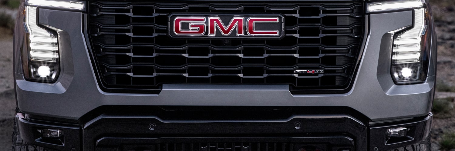 Vue de face d’un GMC Sierra 1500 AT4X gris foncé avec écusson GMC rouge et phares DEL distinctifs