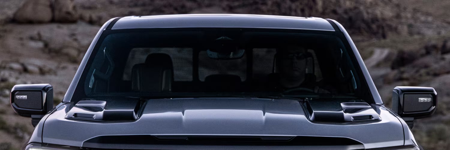 Vue de face d’un GMC Sierra 1500 AT4X gris foncé avec écusson GMC rouge et phares DEL distinctifs