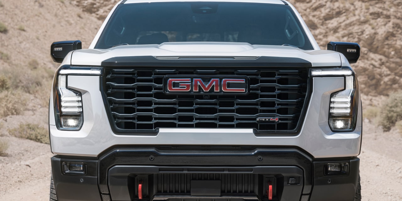 Vue de face d’un GMC Sierra 1500 AT4X blanc avec écusson GMC rouge et phares DEL en forme de C