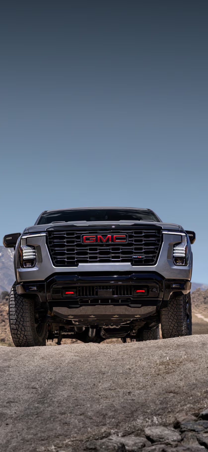 Vue de face d’un GMC Sierra 1500 2027 gris dans un paysage montagneux aride