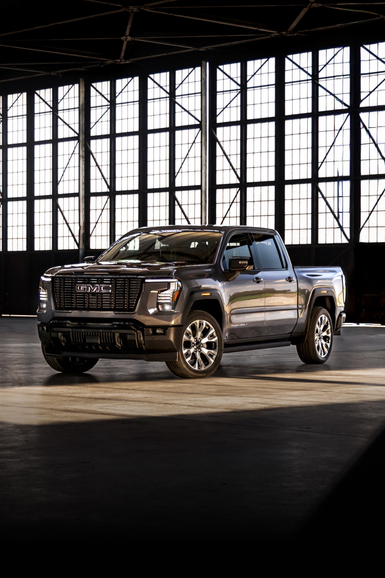 GMC Sierra 1500 Denali gris foncé stationné dans un grand bâtiment industriel baigné de lumière