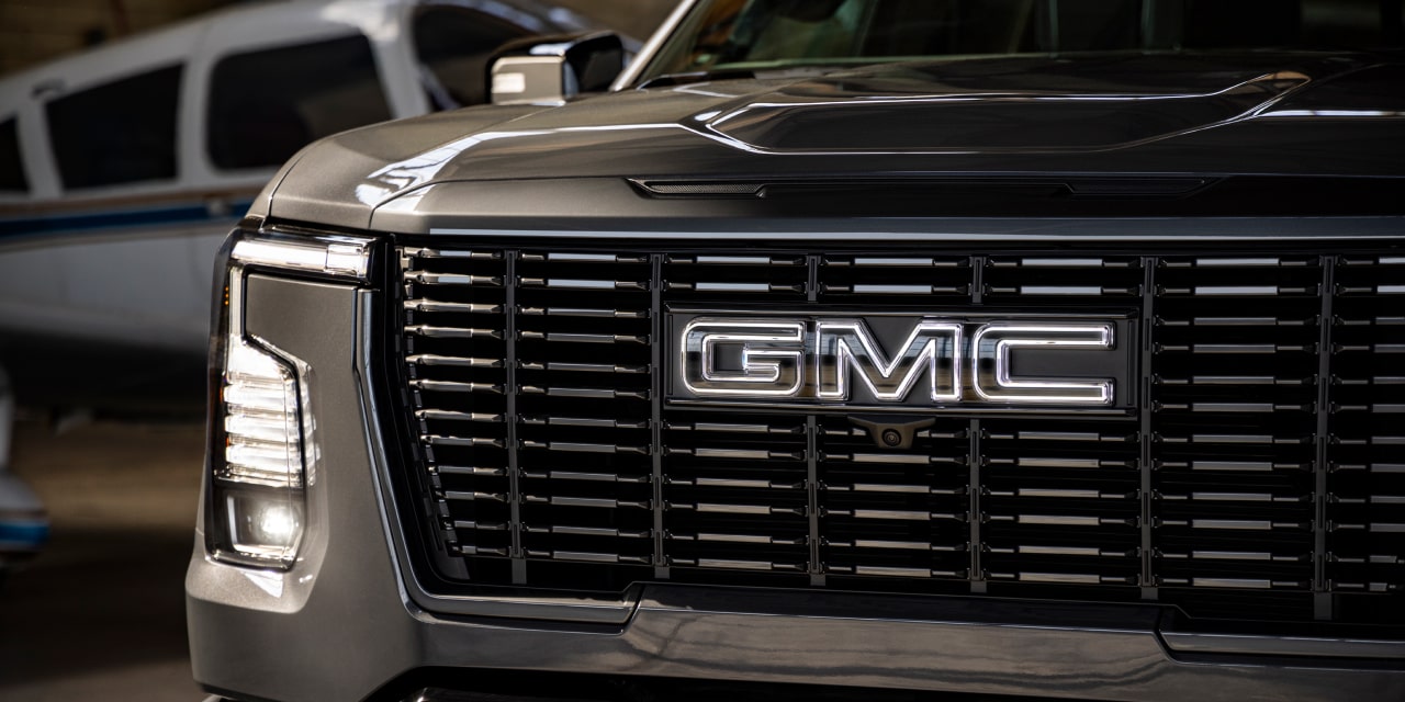 Gros plan sur la calandre avant d’un GMC Sierra 1500 foncé avec logo GMC illuminé