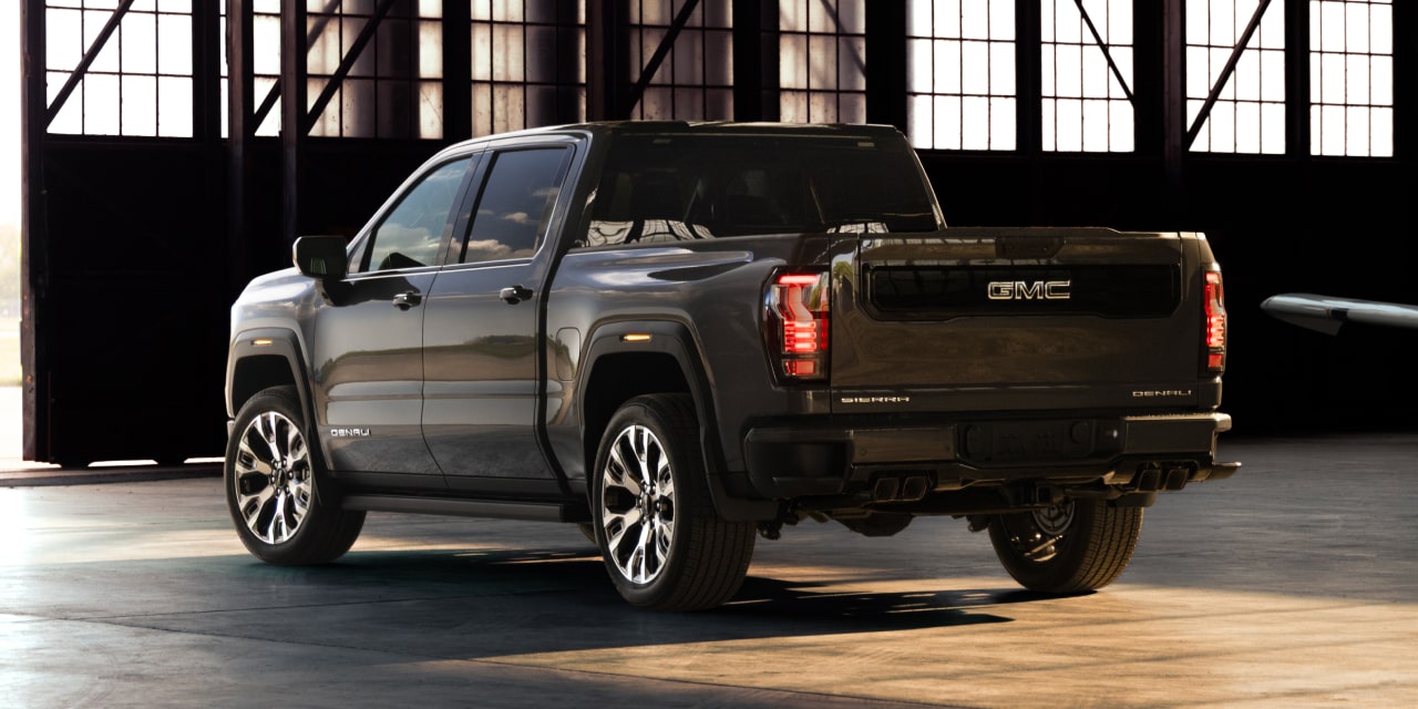 Vue de trois quarts arrière d’un GMC Sierra 1500 Denali foncé stationné dans un hangar avec une aile d’avion