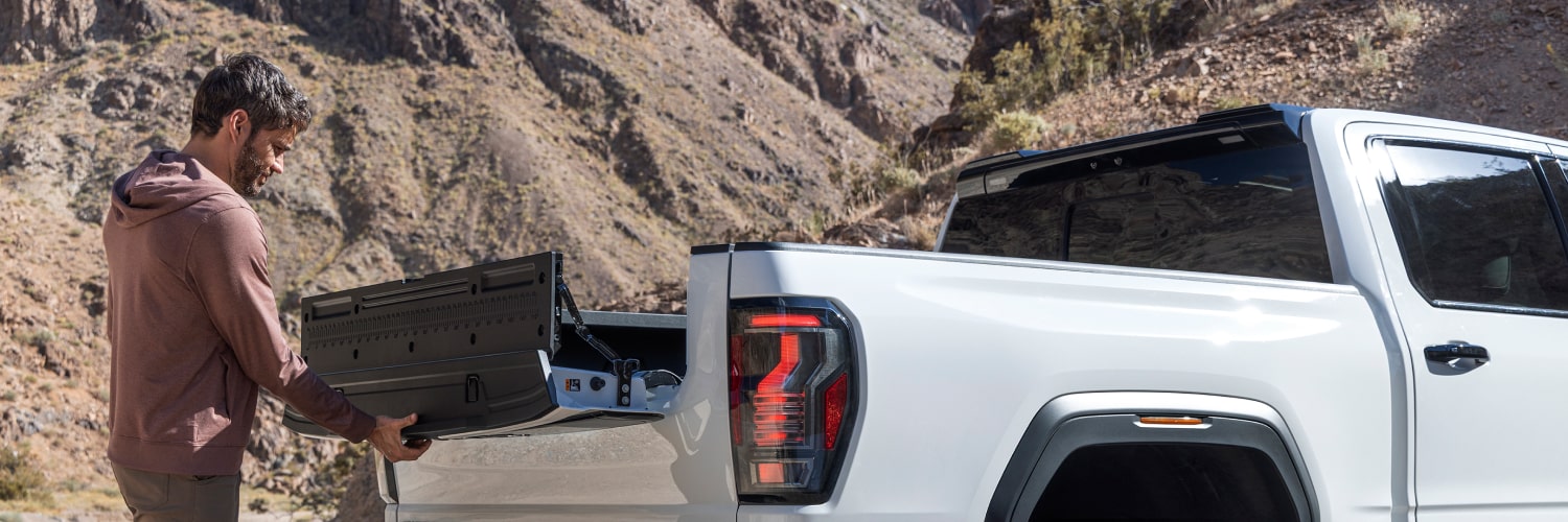 GMC Sierra 1500 2027 gris foncé remorquant un bateau blanc sur une remorque au bord de l’eau