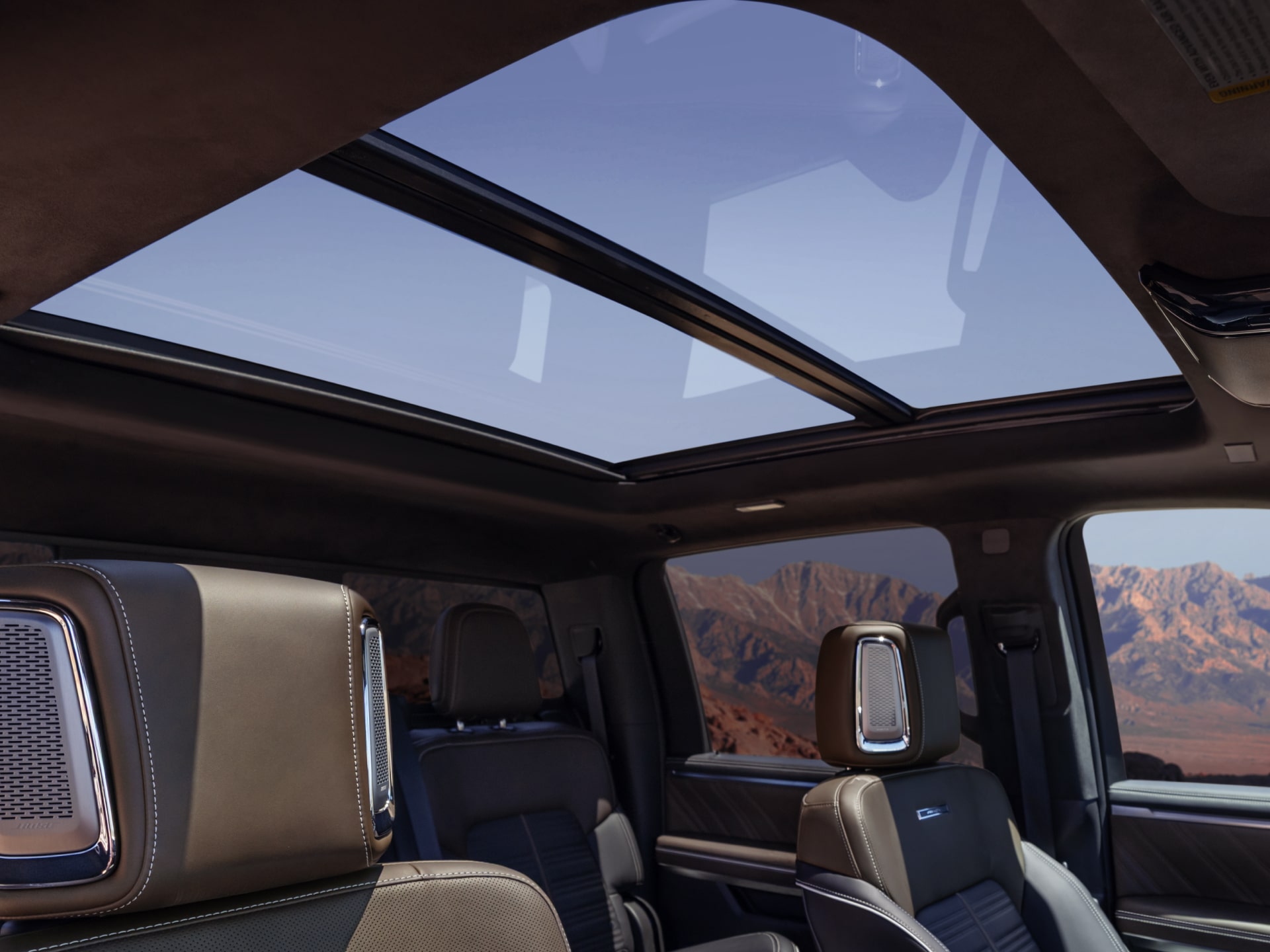 Habitacle du GMC Sierra 1500 2027 avec des sièges bruns et noirs et des montagnes en arrière-plan