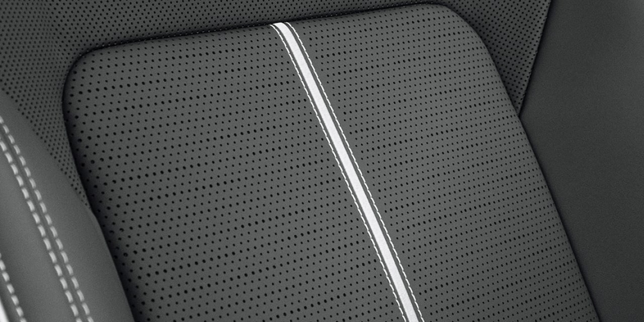 Très gros plan sur la texture d’un siège en cuir noir perforé avec bande verticale blanche