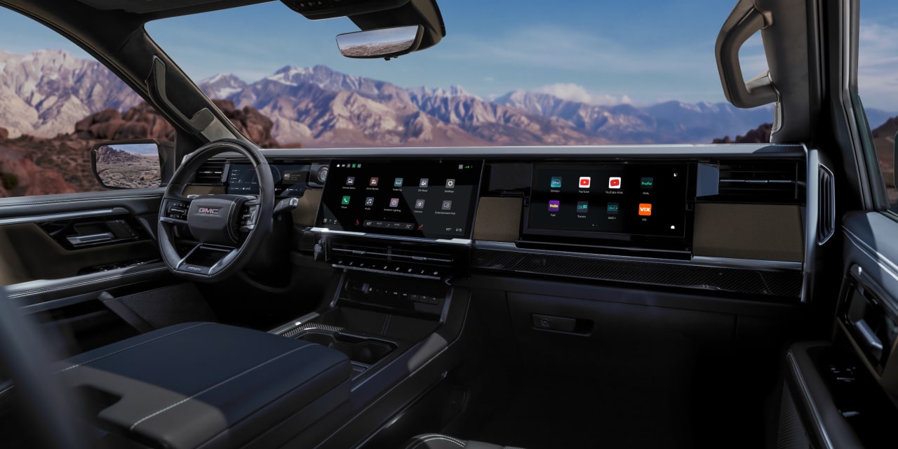 Vue de l’habitacle du GMC Sierra 1500 avec tableau de bord, large écran d’infodivertissement et paysage montagneux