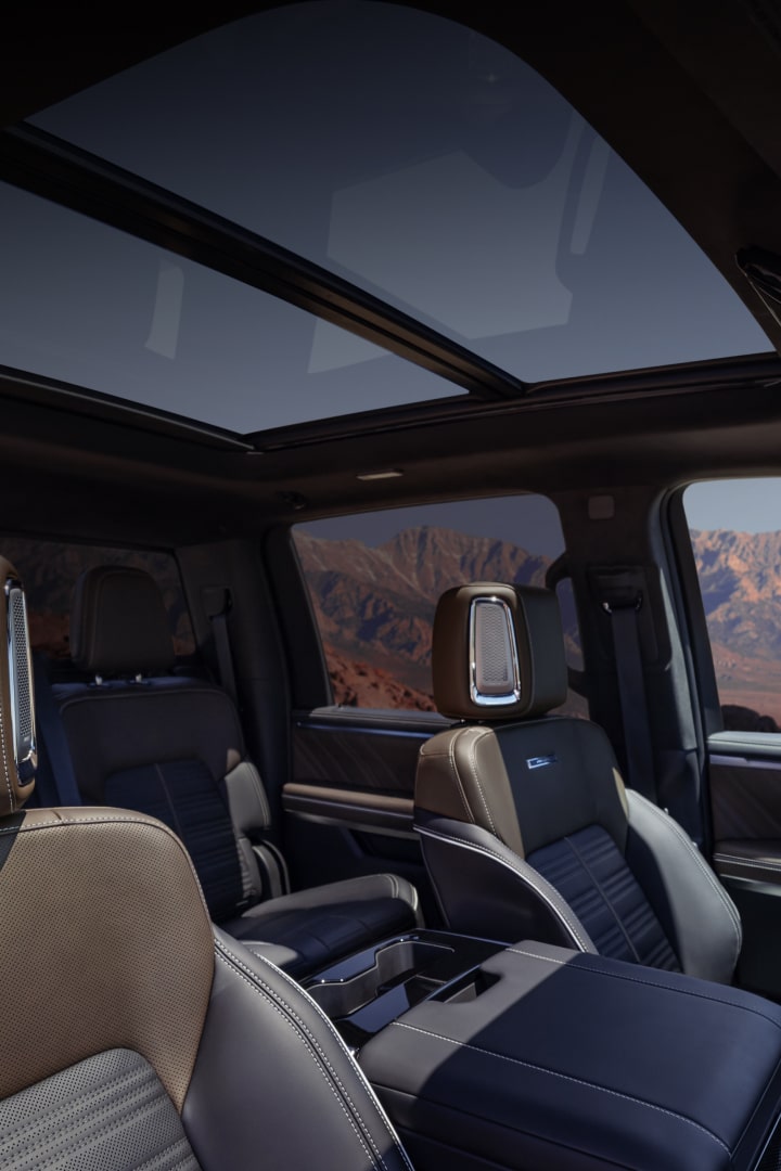 Habitacle du GMC Sierra 1500 2027 avec des sièges bruns et noirs et des montagnes en arrière-plan