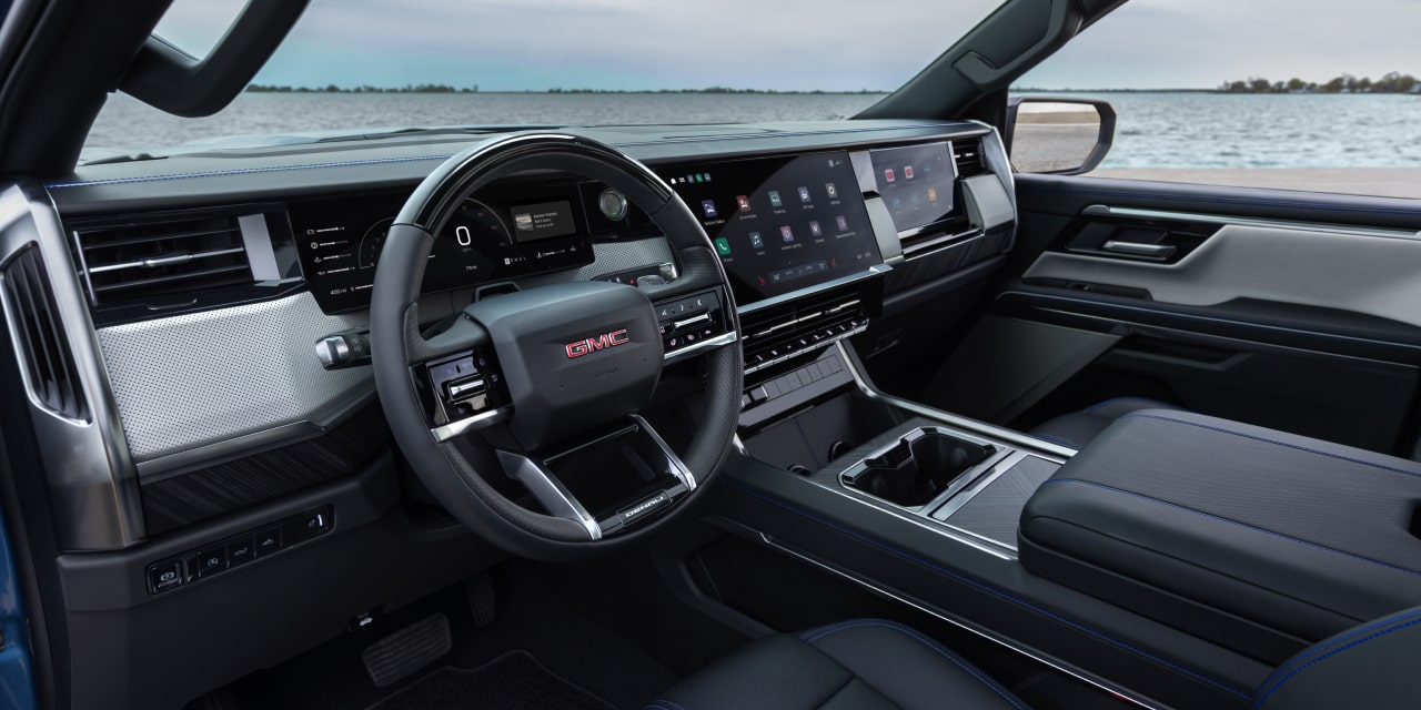 Vue du conducteur de l’habitacle du GMC Sierra 1500 avec accents bleus et vue sur l’eau à l’extérieur