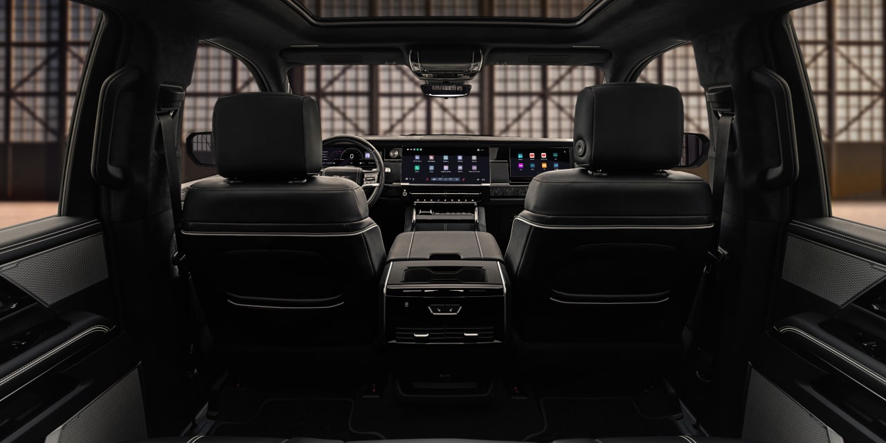 Vue depuis les sièges arrière de l’habitacle du GMC Sierra 1500 2027 avec toit ouvrant et grands écrans