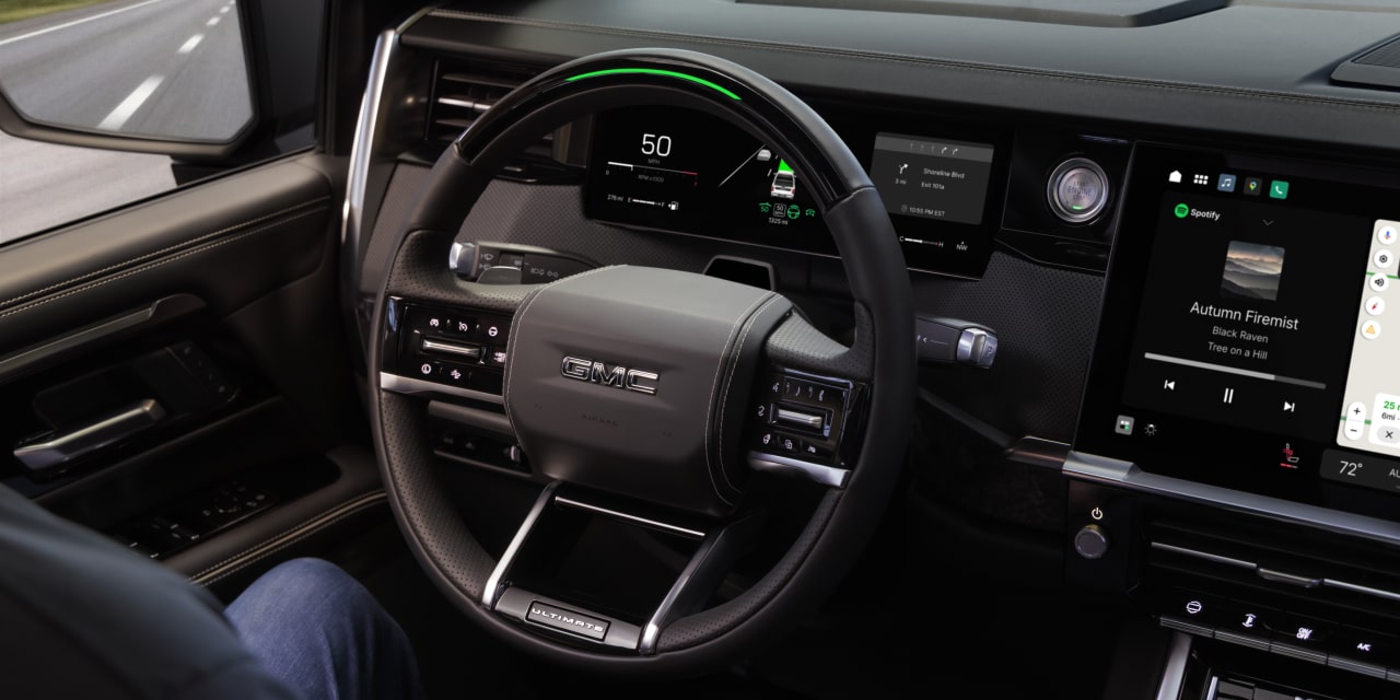 Habitacle d’un GMC Sierra 1500 2027 montrant les mains du conducteur posées sur ses genoux près du volant