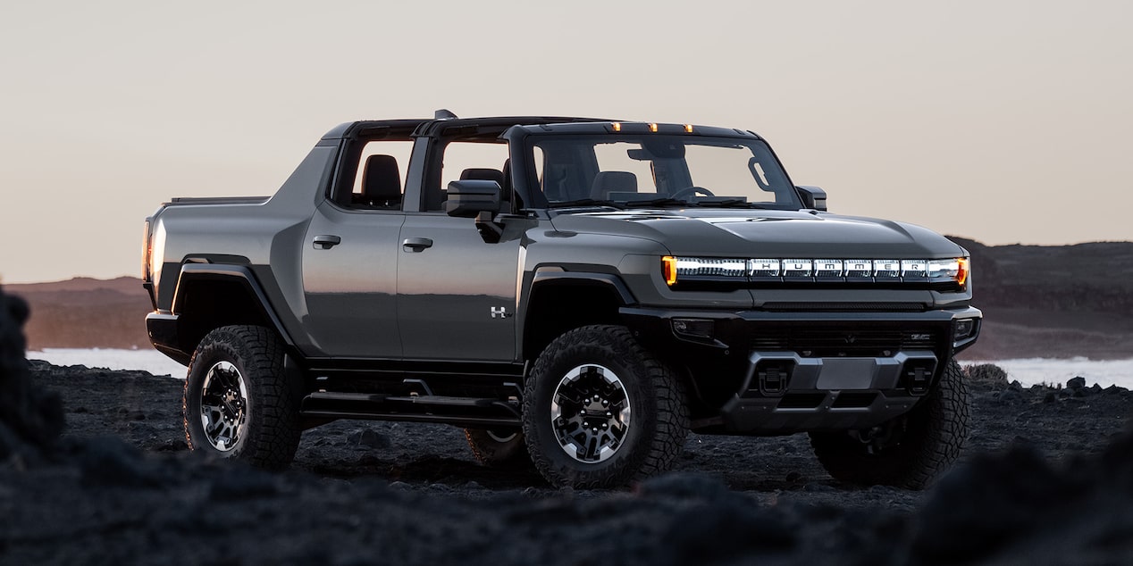 Vue latérale avant du camion HUMMER EV 2026 stationné sur un terrain accidenté.